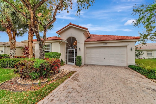 12589 Via Ravenna, Boynton Beach, FL 33436 - mediterranean / spanish-style house featuring a tile roof, decorative driveway, an attached garage, and stucco siding