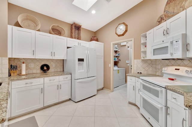 12589 Via Ravenna, Boynton Beach, FL 33436 - kitchen featuring light tile patterned floors, vaulted ceiling with skylight, white appliances, white cabinetry, and open shelves