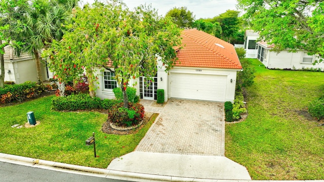 12589 Via Ravenna, Boynton Beach, FL 33436 - view of front of property featuring a front yard, stucco siding, a garage, a tile roof, and decorative driveway