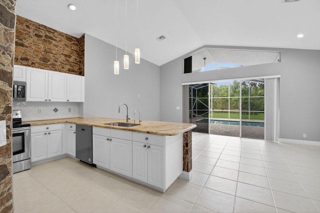 9025 Long Lake Palm Dr, Boca Raton, FL 33496 - kitchen featuring a sink, appliances with stainless steel finishes, lofted ceiling, a peninsula, and white cabinetry