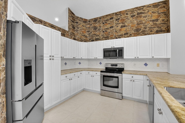 9025 Long Lake Palm Dr, Boca Raton, FL 33496 - kitchen with appliances with stainless steel finishes, tasteful backsplash, light stone countertops, white cabinetry, and a towering ceiling