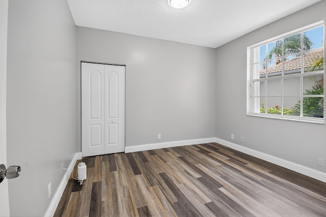 9025 Long Lake Palm Dr, Boca Raton, FL 33496 - unfurnished bedroom with dark wood finished floors, baseboards, and a closet