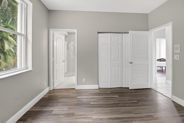 9025 Long Lake Palm Dr, Boca Raton, FL 33496 - unfurnished bedroom featuring multiple windows, dark wood-style floors, and a closet