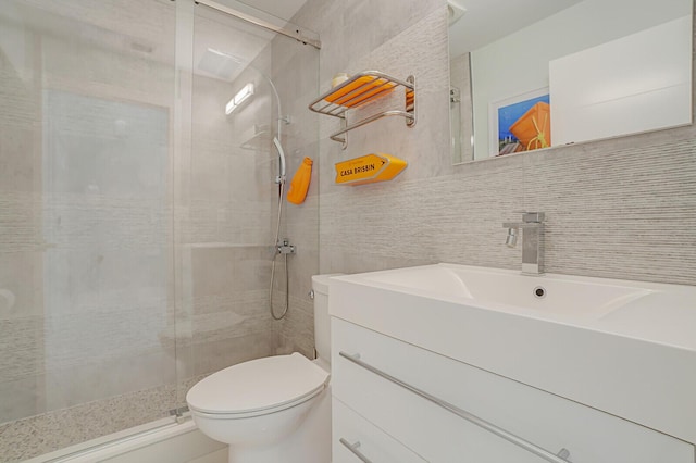 bathroom featuring a shower stall, toilet, tile walls, and vanity