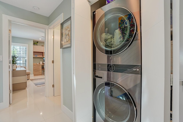 clothes washing area with tile patterned floors, laundry area, and stacked washer and clothes dryer