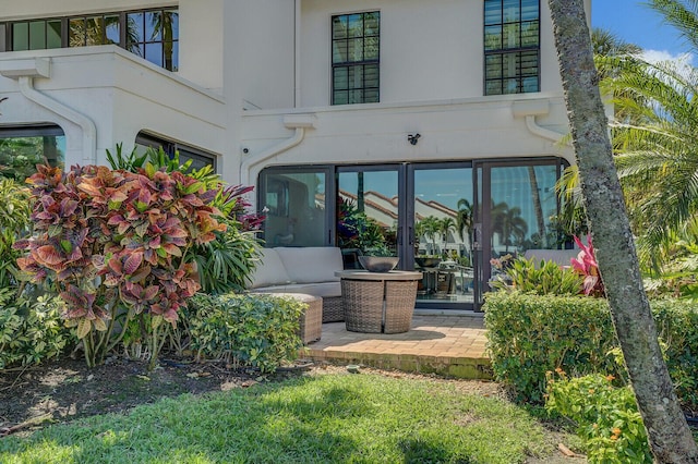 rear view of house with stucco siding and outdoor lounge area