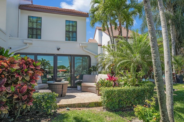 rear view of house with a tiled roof, french doors, and a patio