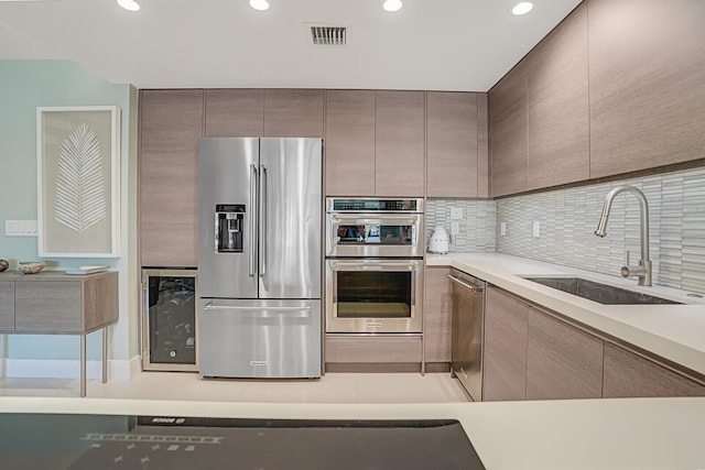 kitchen with visible vents, backsplash, a sink, stainless steel appliances, and modern cabinets