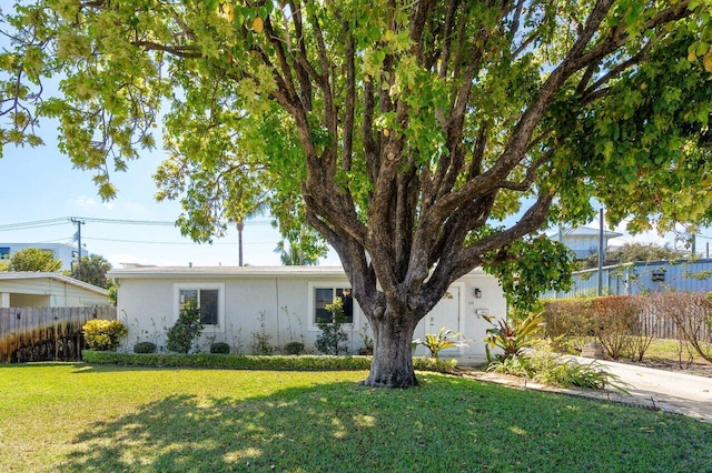 view of front of home with stucco siding, a front yard, and fence