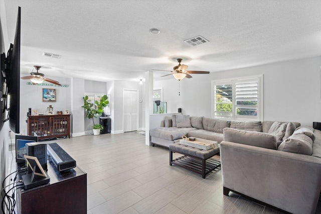 living room with visible vents, a textured ceiling, and ceiling fan