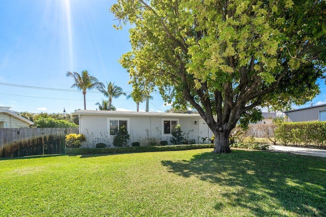 single story home with stucco siding, a front lawn, and fence