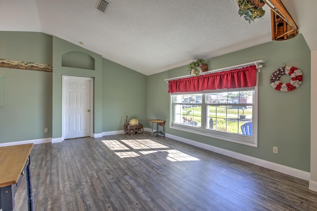 unfurnished room featuring vaulted ceiling, visible vents, baseboards, and wood finished floors