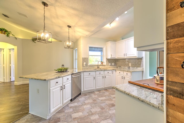 kitchen with backsplash, vaulted ceiling, a peninsula, stainless steel dishwasher, and a sink