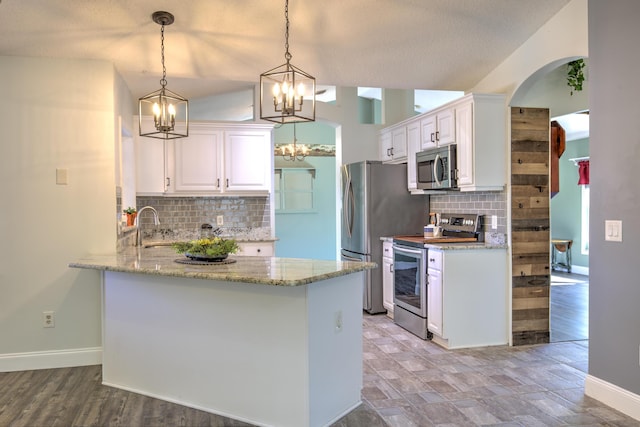 kitchen with an inviting chandelier, a peninsula, white cabinets, and appliances with stainless steel finishes