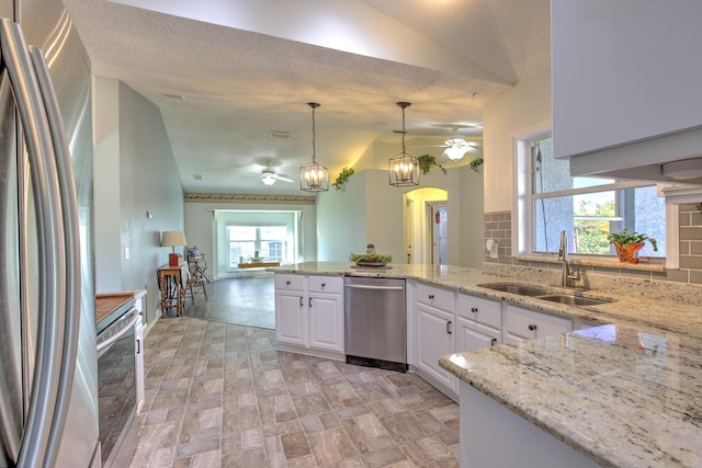 kitchen with a sink, backsplash, appliances with stainless steel finishes, white cabinets, and ceiling fan