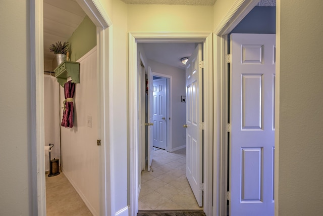 hallway with light tile patterned floors and baseboards