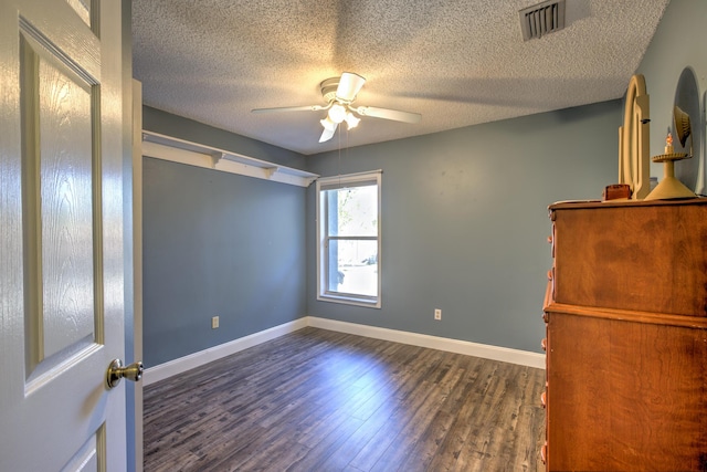 spare room with visible vents, baseboards, a textured ceiling, a ceiling fan, and dark wood-style flooring