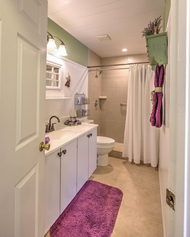bathroom featuring vanity, visible vents, a tile shower, tile patterned flooring, and toilet