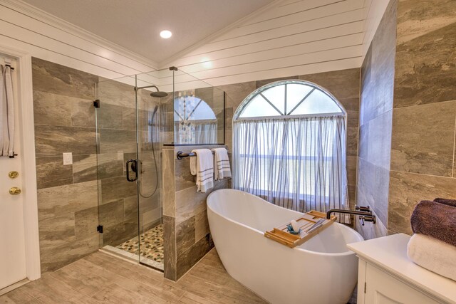 full bath with tile walls, a shower stall, and vaulted ceiling