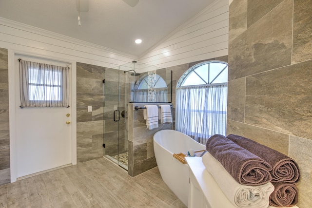 bathroom with vaulted ceiling, a healthy amount of sunlight, a stall shower, and a freestanding bath
