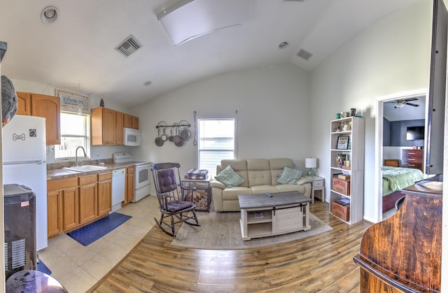 living room with light wood finished floors, visible vents, and vaulted ceiling