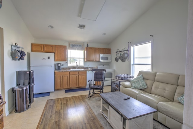 living area with visible vents, light wood-style floors, and vaulted ceiling