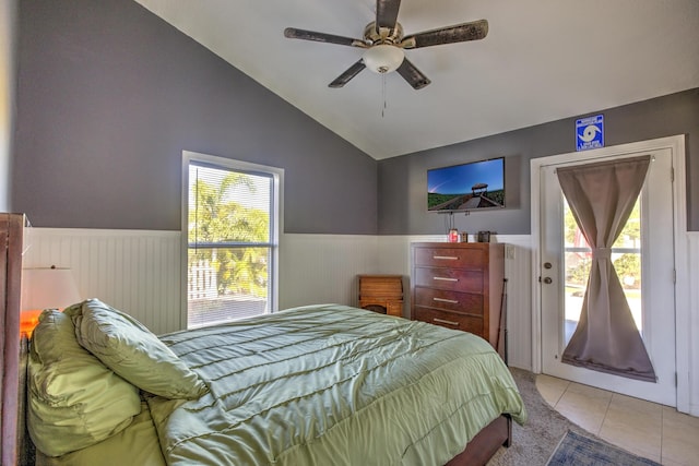 tiled bedroom featuring vaulted ceiling, access to outside, multiple windows, and a wainscoted wall