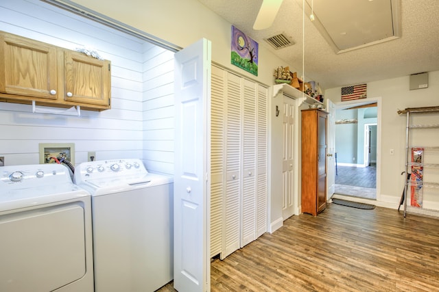 laundry room with visible vents, washer and dryer, a textured ceiling, wood finished floors, and cabinet space