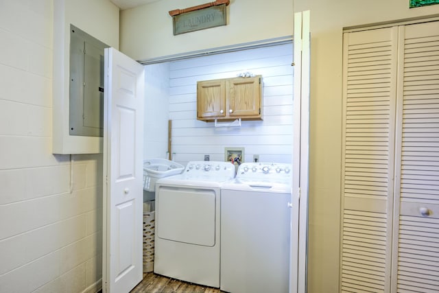 washroom with electric panel, wood finished floors, washing machine and dryer, and laundry area
