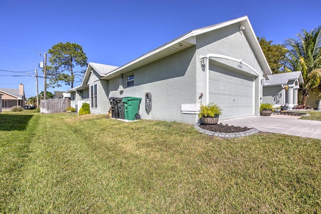 view of side of property with an attached garage, a lawn, driveway, and stucco siding