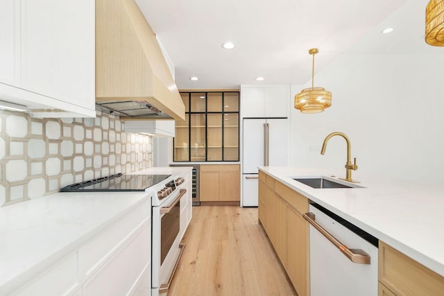 kitchen featuring white appliances, decorative backsplash, custom range hood, light wood finished floors, and a sink