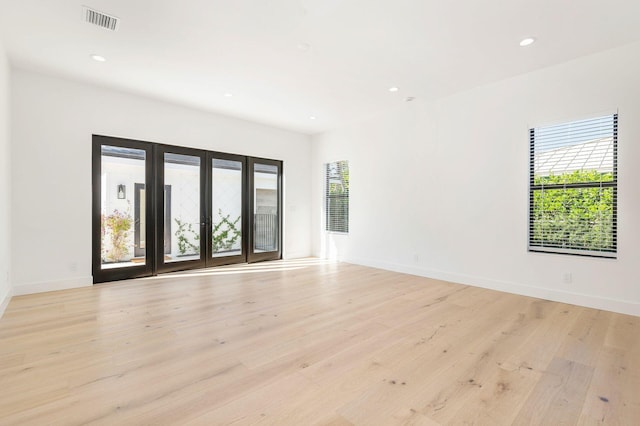 spare room with baseboards, light wood-style flooring, and plenty of natural light