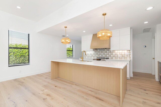 kitchen featuring light wood-type flooring, visible vents, custom range hood, and light countertops