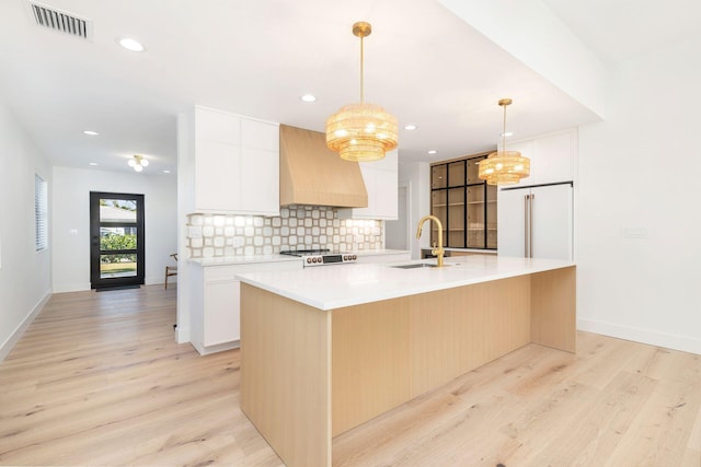 kitchen with an inviting chandelier, custom exhaust hood, light wood-style floors, high end white refrigerator, and a sink