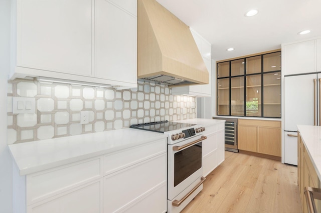 kitchen featuring light countertops, premium range hood, light wood finished floors, white appliances, and backsplash
