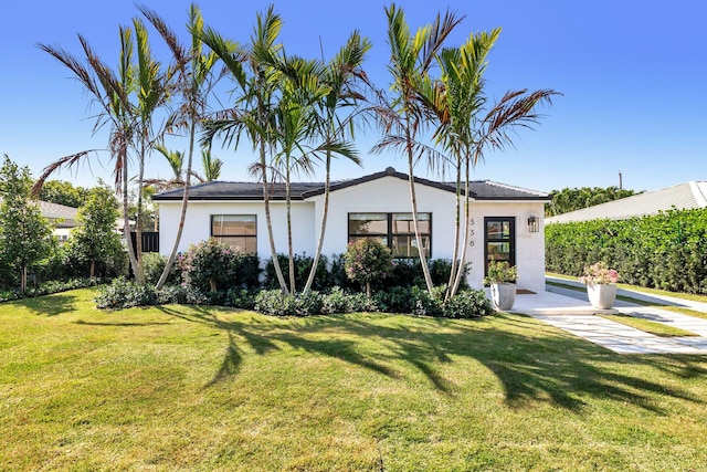 ranch-style home featuring a front lawn and stucco siding