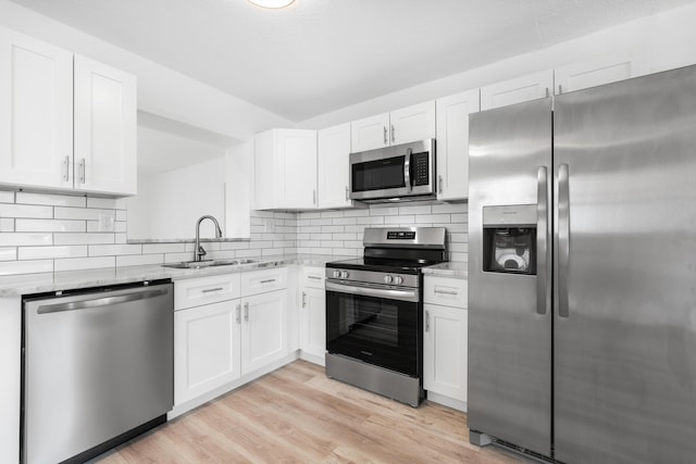 991 SW 31st St, Fort Lauderdale, FL 33315 - kitchen featuring light wood finished floors, decorative backsplash, white cabinets, stainless steel appliances, and a sink
