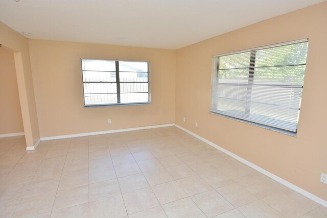 empty room featuring baseboards and light tile patterned floors