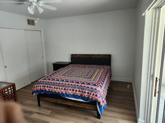 bedroom with visible vents, a ceiling fan, wood finished floors, a closet, and baseboards