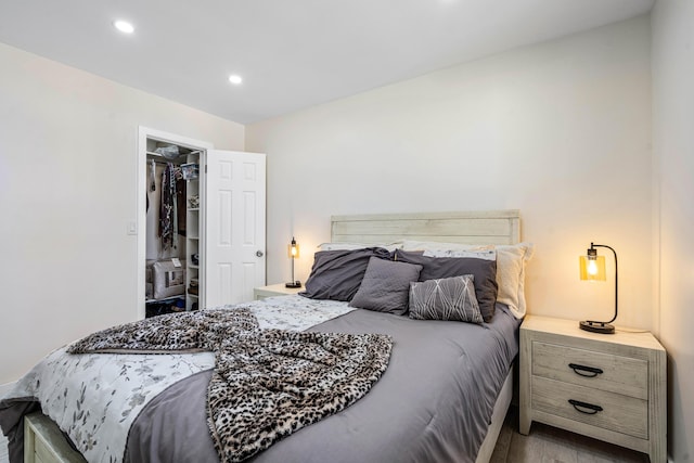 bedroom featuring a walk in closet, wood finished floors, and recessed lighting
