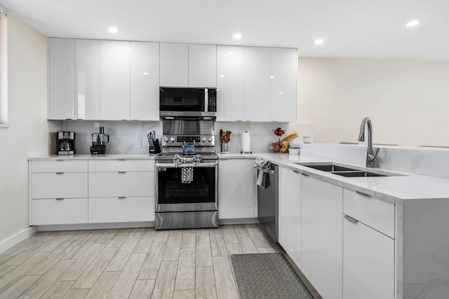 kitchen featuring a sink, stainless steel appliances, modern cabinets, and white cabinets