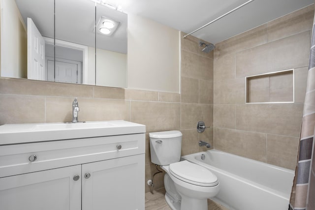 bathroom with vanity, tile walls, toilet, and shower / bath combo