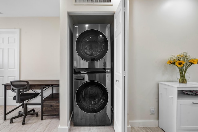 washroom with visible vents, baseboards, light wood-style floors, and stacked washer / dryer