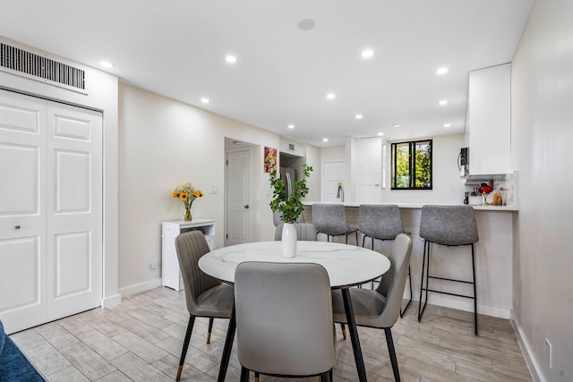 dining area with light wood finished floors, visible vents, and recessed lighting