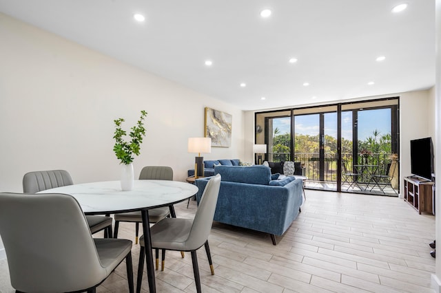 dining area with light wood finished floors, recessed lighting, and a wall of windows