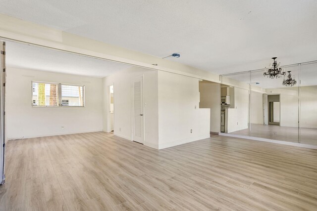 3212 NE 8th Ct Unit 7, Pompano Beach, FL 33062 - unfurnished room featuring a chandelier, light wood-style flooring, and baseboards