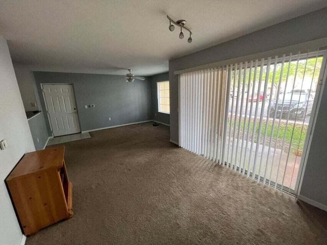 unfurnished living room with carpet, baseboards, and ceiling fan