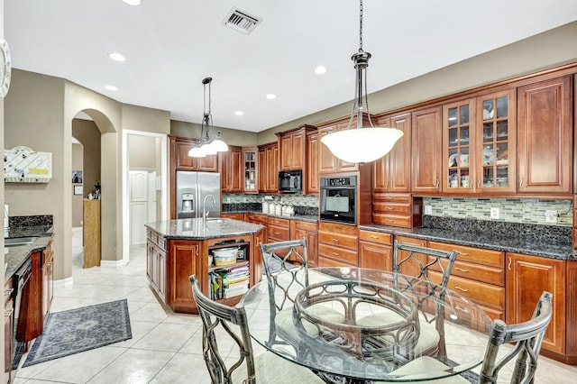 3434 Vanderbilt Dr, Wellington, FL 33414 - kitchen with brown cabinetry, visible vents, arched walkways, decorative backsplash, and black appliances