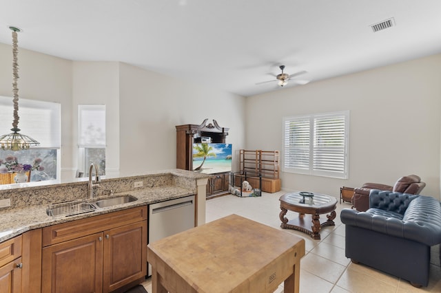 kitchen featuring light stone countertops, a ceiling fan, a sink, open floor plan, and brown cabinetry