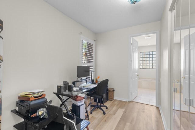 office with baseboards, a healthy amount of sunlight, and wood finished floors